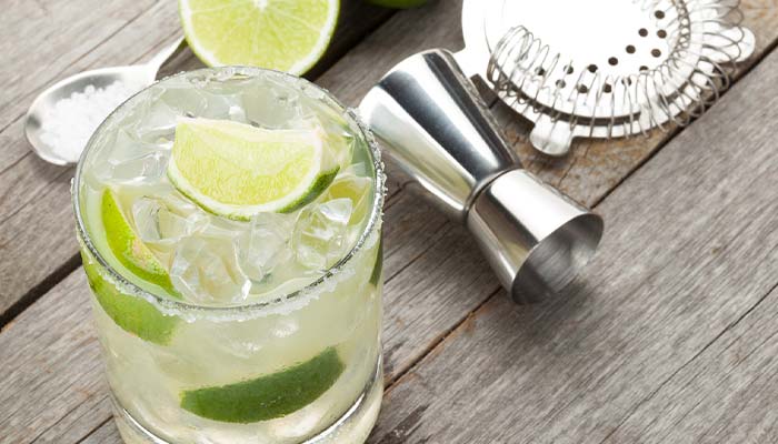 A cocktail with ice and lime sits by a jigger at Bar & Drinks Dilworth MN.